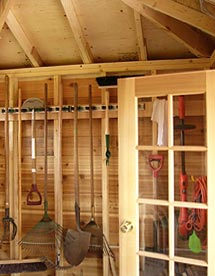 garden shed interior showing spruce framing, cedar French door and garden tools neatly arranged.